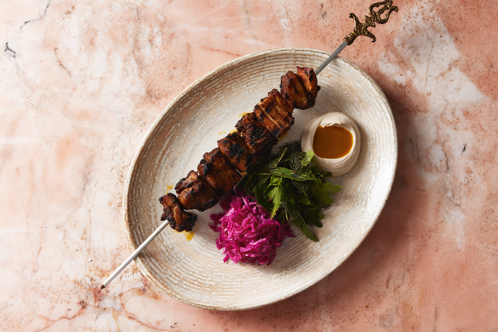 Chicken shawarma skewer with tahini, pickled cabbage, and fresh herbs on a rustic plate – Middle Eastern dining at Shaffa.