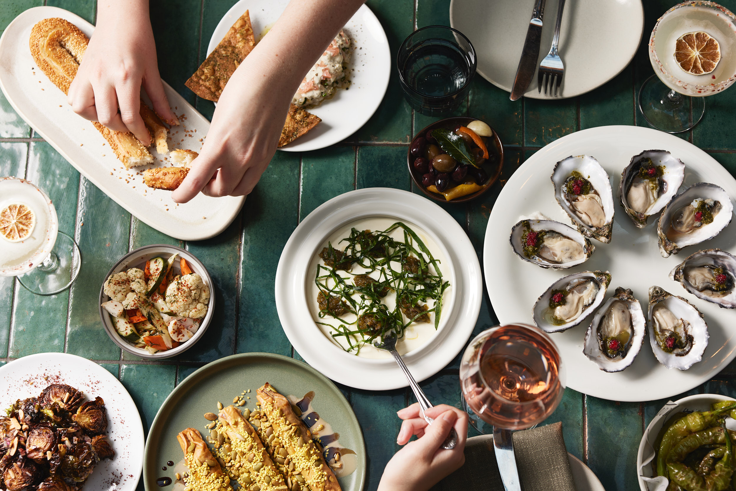 A vibrant Middle Eastern feast at Shaffa, featuring oysters, mezze, and fresh cocktails, served on a green-tiled table in Surry Hills.