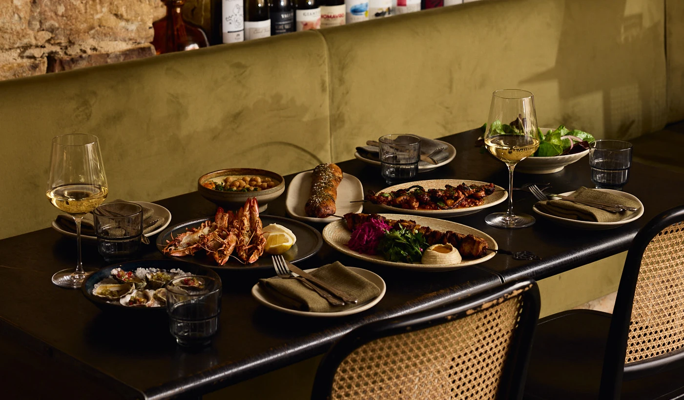Middle Eastern feast on marble table with meats, salads, hummus, dips, and wine at a Surry Hills restaurant.